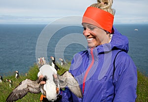 Happy young woman holding puffin in Iceland