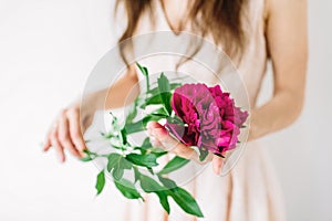 Happy young woman holding red peony in hands. Sweet romantic moment