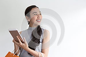 Happy young woman holding shopping bags and mobile phone. Makes online shopping on a tablet