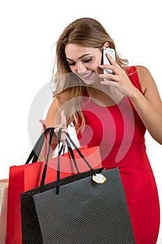 Happy young woman holding shopping bags and mobile phone over white background