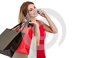 Happy young woman holding shopping bags and mobile phone over white background