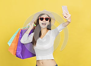 Happy young woman holding shopping bags and watching the mobile phone