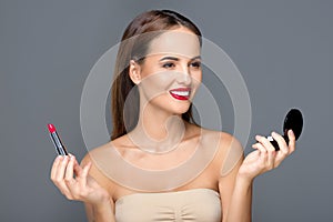 happy young woman holding small mirror and lipstick