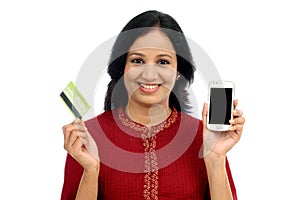 Happy young woman holding smart phone and credit card