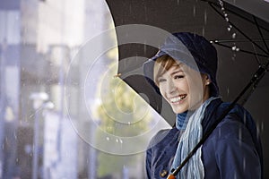 Happy young woman holding umbrella in rain