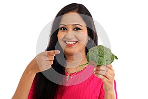 Happy young woman holdong broccoli