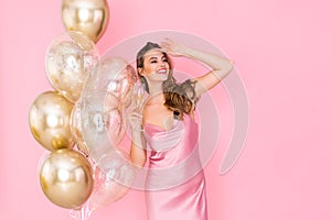 Happy young woman holds glass of champagne stands near air balloons. came to party. Celebration