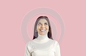 Happy young woman isolated on pink background thinking, dreaming, looking up and smiling