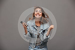 Happy young woman in jeans jacket clenching her fists in winner photo