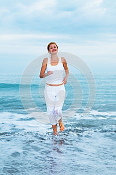 Happy young woman is jumping in the beach