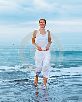 Happy young woman is jumping in the beach