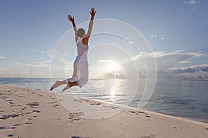 Happy young woman jumping on the beach