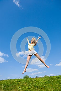 Happy young woman is jumping in a field