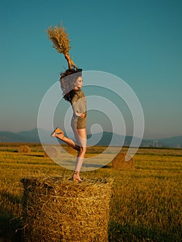 Happy, young woman jumping on hay stack