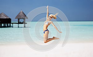 Happy young woman jumping over exotic beach