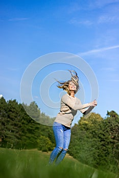 Happy young woman jumping, sky and tree background