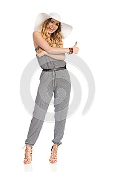 Happy Young Woman In Jumpsuit And Sun Hat Is Showing Thumb Up