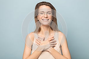 Happy young woman keep hands at chest feeling grateful