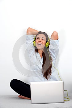 Happy young woman with laptop and earphones