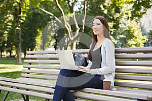 Happy young woman with laptop outdoors