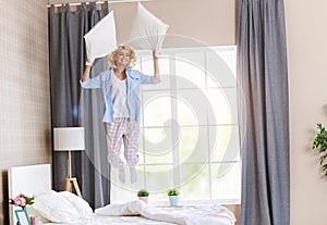 Happy young woman laughing and jumping on the bed in   morning at home