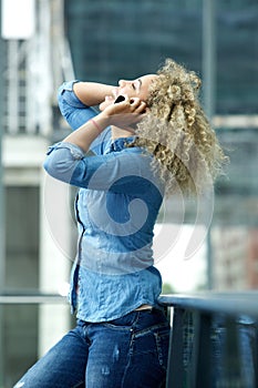 Happy young woman laughing on phone with hand in hair
