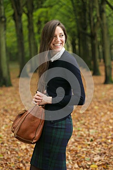 Happy young woman laughing and walking outdoors with bag