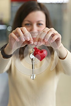 Happy young woman with leather red heart key trinket as a valentines day gift close up photo
