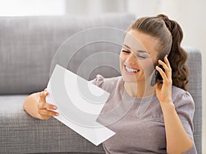Happy young woman with letter talking cell phone