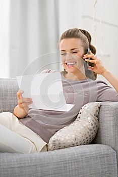 Happy young woman with letter talking cell phone