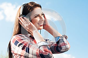 Happy young woman listening to music under the blue sky