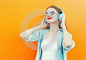 Happy young woman listens and enjoys music in headphones