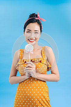 Happy young woman with lollipop candy isolated on blue
