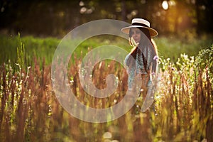 Happy young woman with long hair in a hat in a field