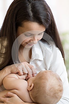 Happy young woman looking at baby. Healthy nutrition, breastfeeding and maternity concept.