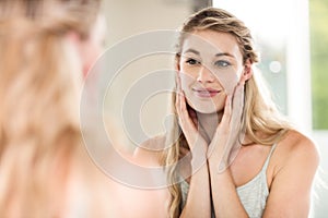 Happy young woman looking in mirror