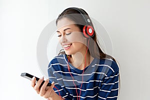 Happy young woman looking at mobile phone and listening to music with headphones