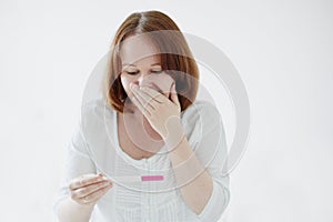 Happy young woman looking at positive pregnancy test