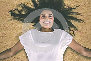 Happy young woman lying down on the dried grass