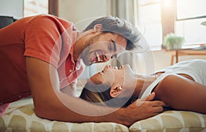 Happy young woman lying down while her boyfriend leans over her as they laugh together and look into each other eyes