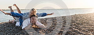 Happy young woman lying on her boyfriends back, looking at camera, having fun together. Wide photography.