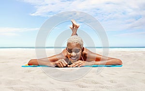 Happy young woman lying on sand beach, on a sunny day by the seaside, concept of a summer beach holiday, booking travel and resort