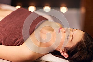 Happy young woman lying at spa or massage parlor