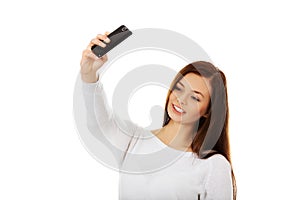 Happy young woman makes selfies with smart phone