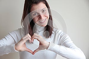 Happy young woman making heart shape with hands