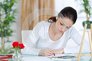 Happy young woman making sketches in art class