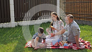 Happy young woman and man sit with little boy on lawn