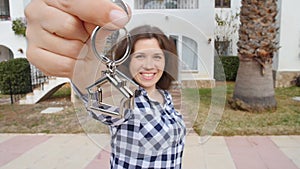 Happy young Woman moving into new home. Showing keys of new property