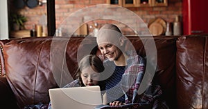 Happy young woman with oncology remission using computer with daughter.