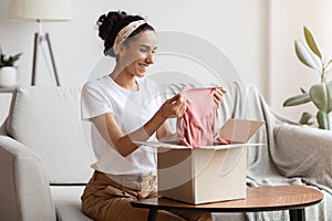 Happy young woman opening carton box, checking delivery, copy space
